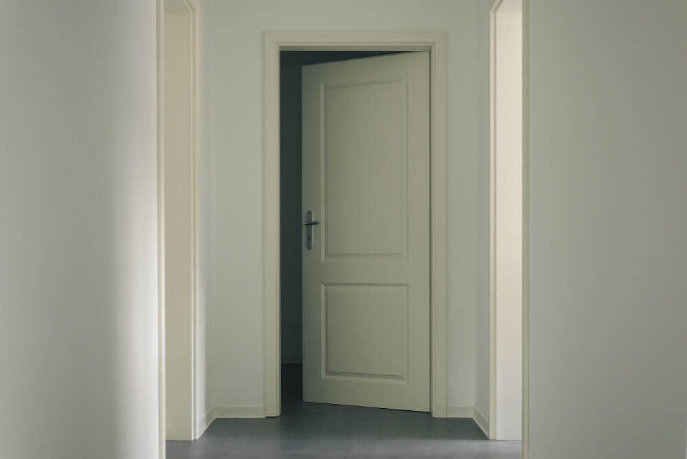 Отворена бяла врата в коридор с первази